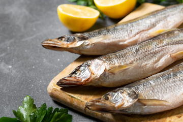 Smoked or dried fish smelt on a wooden Board on a gray kitchen table