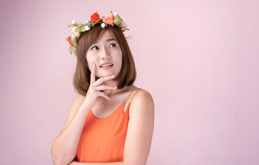 Asian woman wearing a crown of flowers with beautiful bouquet of flowers on a nice day with a pink background,Fashion model having fun.