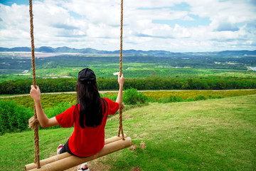 Female tourists sit and swing on the top of the high hill