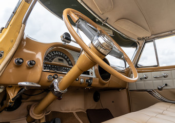 Interior and dash board of a classic car with the steering wheel and the dashboard showing