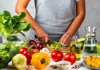 Woman cuts avocado and cooking salad in the kitchen. Healthy diet concept.