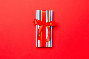 Gift box with red bow for Christmas or New Year day on red background, top view with copy space