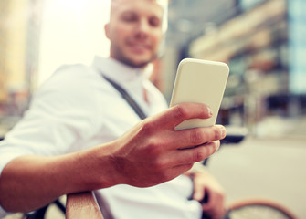 technology, communication and people concept - close up of man texting message on smartphone in city