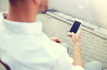 technology, communication and people concept - close up of man texting message on smartphone in city