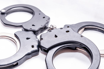 Two pair of handcuffs, one black and the other black and silver on a white background