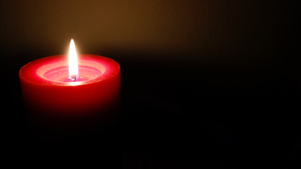 Red candle burning light in the dark background, Christmas and spa decoration, space for text