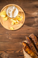 Beer glass with beer and hot smoked fish close-up. Beer mug with beer and potato chips, crackers on a dark background and copy space.