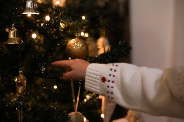 Child points a finger at the Christmas tree. Baby helps to decorate a Christmas tree - 309395626