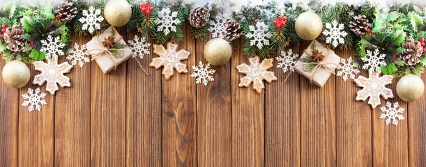 Christmas gifts, Christmas gingerbread cookie, snowflakes, Christmas tree branches and cones on a wooden background. View from above