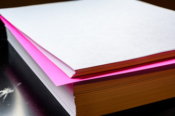 Single colored sheet in a stack of plain white paper