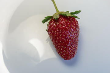 Freshly picked strawberry on a white dish. Concept of vegan dessert.
