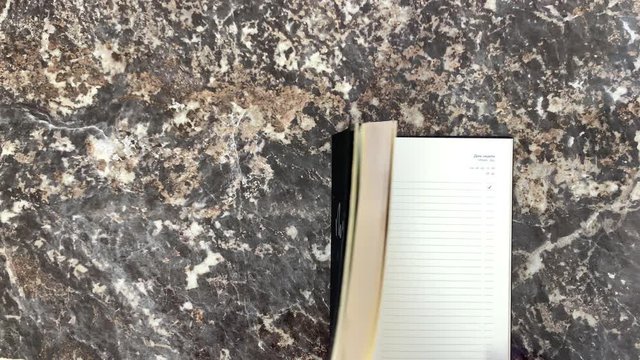 Incredible cosmic beautiful black diary on a black marble background, opens and you can make notes. Scrolling pages. Top view.
