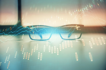Financial graph hologram with glasses on the table background. Concept of business. Double exposure.