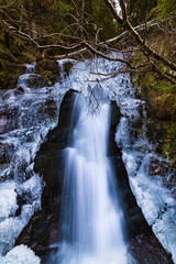 A small active waterfall. Clean mountain stream, snowy winter landscape, wildlife background