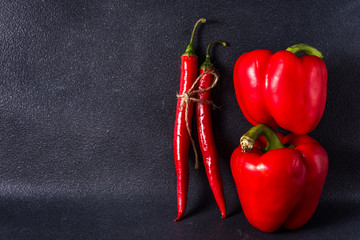 red sweet and hot chili peppers on a dark background with place for text