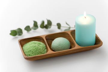 Obraz na płótnie Canvas beauty, spa and wellness concept - green bath salt, konjac sponge and candle on wooden tray with eucalyptus cinerea