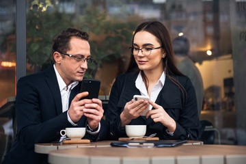 Business people in cafe, working while break. Business-team working on laptop at coffee bar, looking a mobile phone.