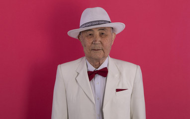 portrait of an old man in a white suit and white hat on a red background