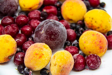 A Berry mix from frozen currant, apricot, plum, cherry. A Frozen Berries from freezer. A sweet background with frozen plum, currant, apricot and cherry. A healthy Berries on the background.