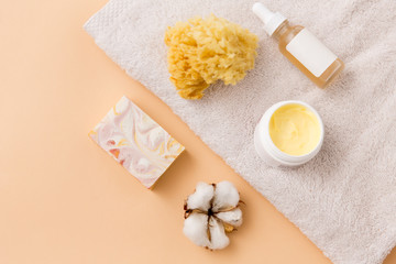beauty, spa and wellness concept - close up of crafted soap bar, body butter, natural sponge and essential oil on bath towel