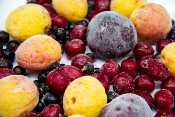 A Berry mix from frozen currant, apricot, plum, cherry. A Frozen Berries from freezer. A sweet background with frozen plum, currant, apricot and cherry. A healthy Berries on the background.