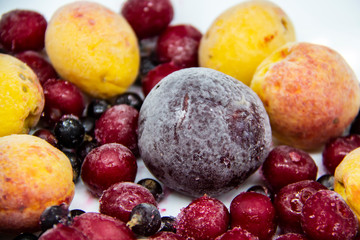 A Berry mix from frozen currant, apricot, plum, cherry. A Frozen Berries from freezer. A sweet background with frozen plum, currant, apricot and cherry. A healthy Berries on the background.