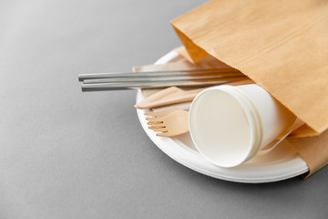recycling and eco friendly concept - set of wooden forks, knives, paper cups and metallic straws...
