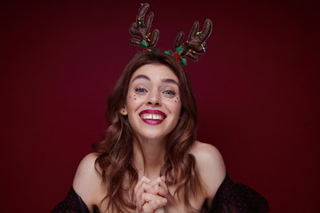 Indoor shot of young joyful lovely brunette with wavy hairstyle enjoying x-mas theme party...
