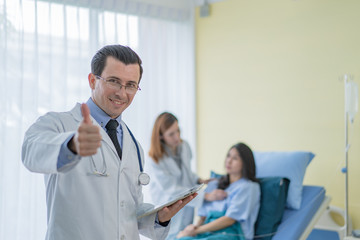 Fototapeta premium A professional doctor standing in a room with a patient lying in bed with an assistant doctor to prepare for a patient check up.