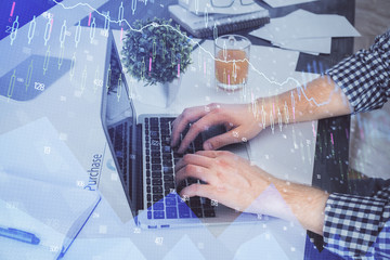 Double exposure of graph with man typing on computer in office on background. Concept of hard work.