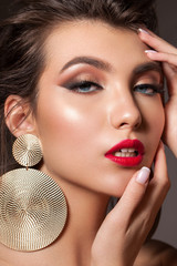 Close up fashion portrait of a very beautiful brunette model with professional makeup, perfect skin and red lips.