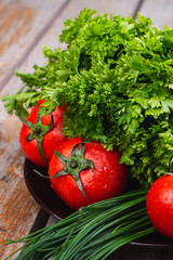 Fresh bright vegetables and herbs on a wooden table.