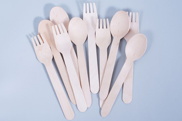 Brown wooden spoons and forks -cutlery lie on a light gray background. The concept of environmental...
