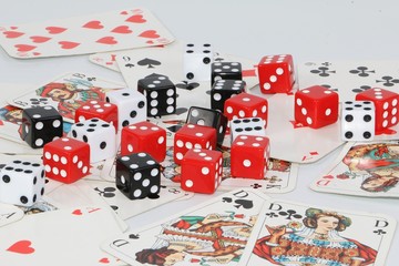 colorful dices lie on a pile of playing cards in the white studio