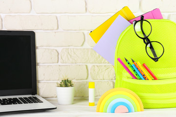 Hipster neon green textile backpack, stuffed with school supplies. Back to school concept. Lots of different stationery items on colorful background. Close up, copy space.