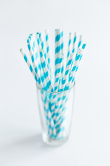 Blue straws for cocktails in a glass on a white background