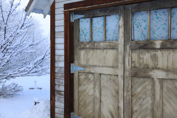 Winter old American Country landscape with rustic houses, cars and fences covered in snow.
