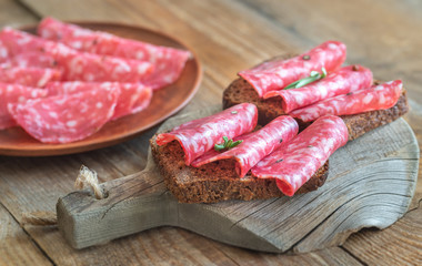 Sandwiches with salami on the wooden board