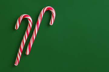 Two christmas red candies on a green paper background.