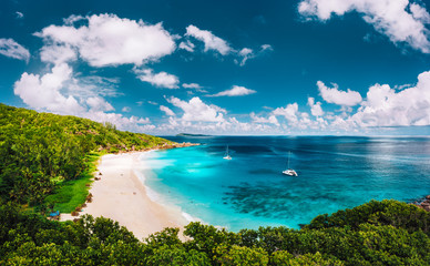 Grand Anse beach at La Digue island in Seychelles aerial panoramic view. White sandy beach with blue ocean lagoon and catamaran yacht moored