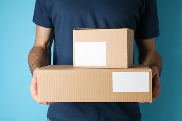 Delivery man hold blank boxes against blue background, space for text