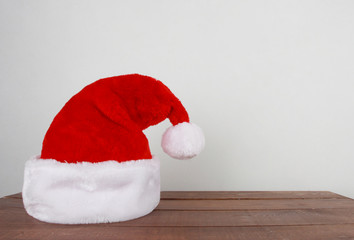 Closeup of Santa Claus hat on dark brown wooden table over  white background. Christmas background. New Year, winter holiday, Santa cap, copy space