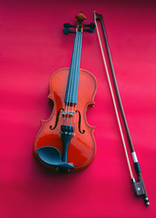 Fototapeta na wymiar The wooden violin and bow put on red background,show detail of string insgrument,art style