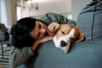 A woman and a dog lie on a sofa and sleep.