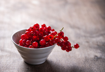 Fresh red currant  in bowl on old brown wood background