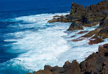 Fototapeta na wymiar Deep blue waves, white foam and spray. Canary Islands. Lanzarote, volcanic island. The magnificent coast of the Atlantic Ocean. February 2019.