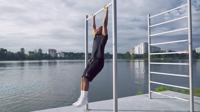 Strong african guy doing abs exercises near lake