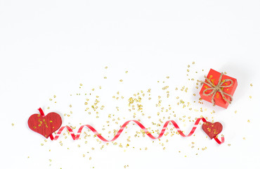 two red wooden hearts one small the other large between them a red twisted and a red gift with a bow sprinkled with small yellow hearts at the bottom of the image on a white background top view