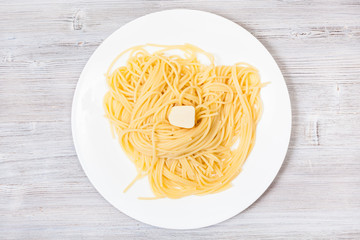 view of pasta with butter on white plate on gray
