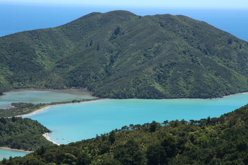 Fototapeta na wymiar Beautiful marine beach landscapes in New Zealand South Island with turquoise blue and green water and hills with thick lush evergreen vegetation